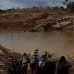 Pessoas caminham perto de uma ponte que desabou durante a cheia do Rio Taquari, em Arroio do Meio, no Rio Grande do Sul - 20/5/2024 | Foto: Amanda Perobelli/Reuters