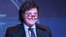 Javier Milei, presidente da Argentina, sorri e usa óculos durante discurso
