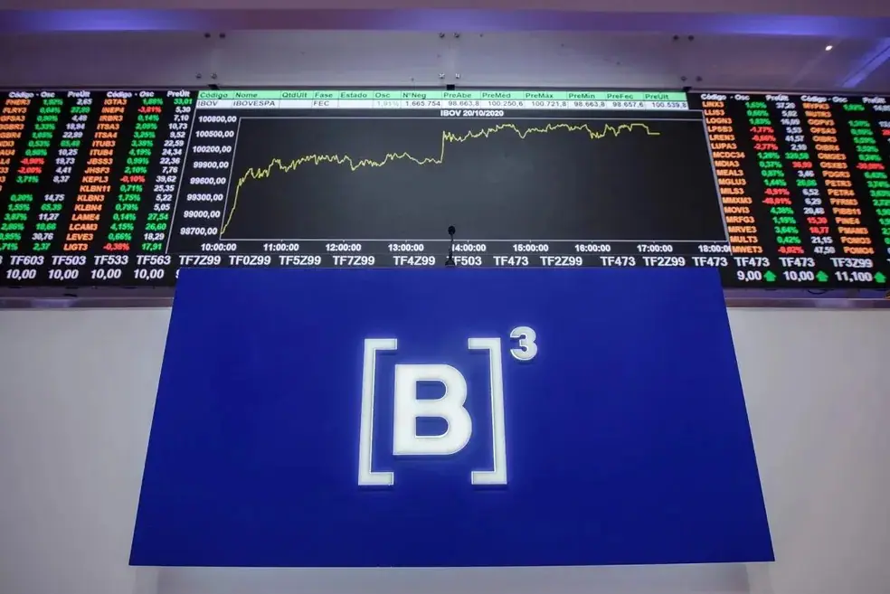 Gráfico do Ibovespa atrás de uma placa do B3, a Bolsa de Valores do Brasil