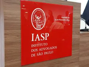 Placa com a logo e o nome do IASP com um fundo vermelho