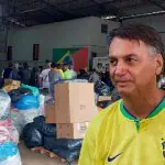 Bolsonaro de camiseta amarela em frente a donativos para o RS