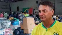 Bolsonaro de camiseta amarela em frente a donativos para o RS