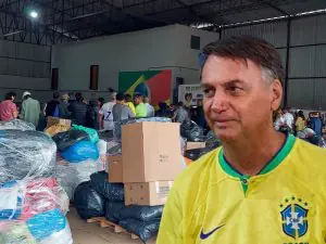 Bolsonaro de camiseta amarela em frente a donativos para o RS