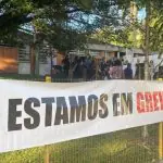 Foto mostra faixa na frente de escola com a mensagem "estamos em greve"