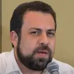 Guilherme Boulos, de camisa branca, aparece com semblante de alguém preocupado durante uma entrevista transmitida pelo canal de Luiz Inácio Lula da Silva no YouTube
