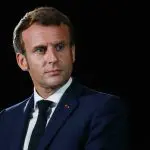Imagem do presidente Emmanuel Macron com terno azul escuro, camisa social branca e gravata escura