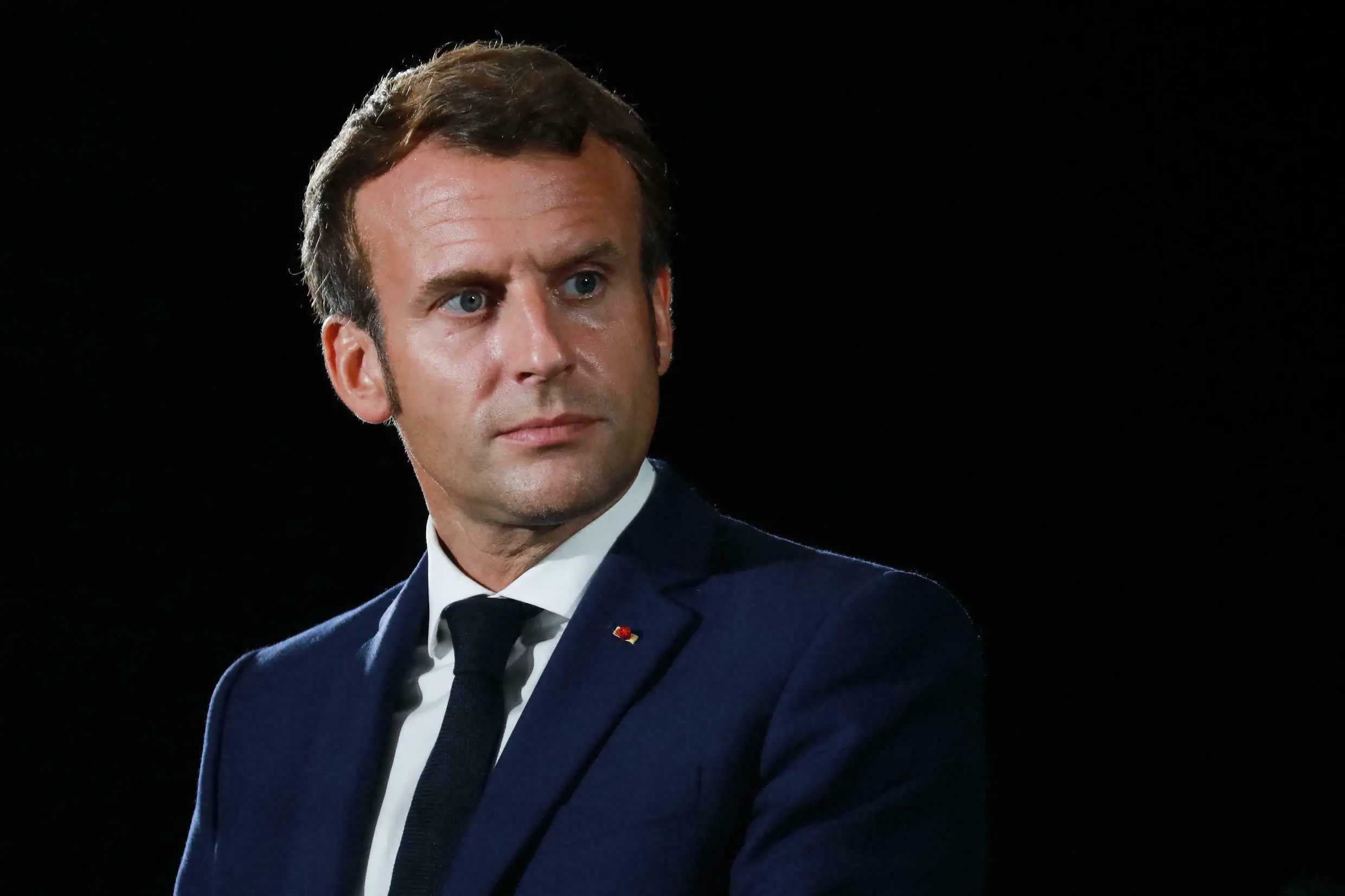 Imagem do presidente Emmanuel Macron com terno azul escuro, camisa social branca e gravata escura