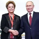A ex-presidente do Brasil Dilma Rousseff e presidente da Rússia, Vladimir Putin, aparecem de mãos dadas, sorrindo para foto