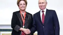 A ex-presidente do Brasil Dilma Rousseff e presidente da Rússia, Vladimir Putin, aparecem de mãos dadas, sorrindo para foto