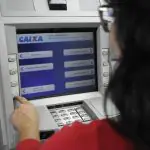 Mulher aparece em caixa eletrônico da Caixa Econômica Federal, simulando um serviço, como o saque do FGTS