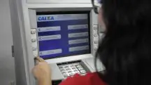 Mulher aparece em caixa eletrônico da Caixa Econômica Federal, simulando um serviço, como o saque do FGTS