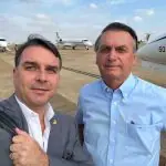 O Senador Flávio Bolsonaro (PL-SP) e ex-presidente do Brasil Jair Bolsonaro aparecem lado a lado em aeroporto, usando roupas sociais