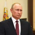 Presidente da Rússia, Vladimir Putin, veste terno preto, camisa social branca e gravata vermelha