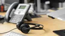 Mesa de madeira com telefone fixo e fone de ouvido em cima