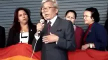 Em pé, o então deputado federal Clodovil Hernandes, que aparece de terno cinza escuro, camisa branca e gravata vinho, critica a Parada Gay; atrás dele aparece a deputada petista Maria do Rosário