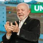 Lula veste blazer preto e camisa social branca enquanto aplaude