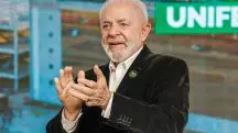 Lula veste blazer preto e camisa social branca enquanto aplaude