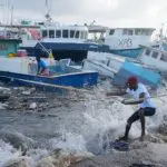 Homens puxam barcos levados pelo furacão Beryl