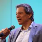 Fernando Haddad veste terno cinza com camisa branca enquanto discursa