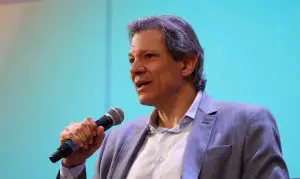 Fernando Haddad veste terno cinza com camisa branca enquanto discursa