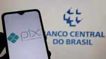 Celular com o app do Pix aberto, com a logo do Banco Central ao fundo