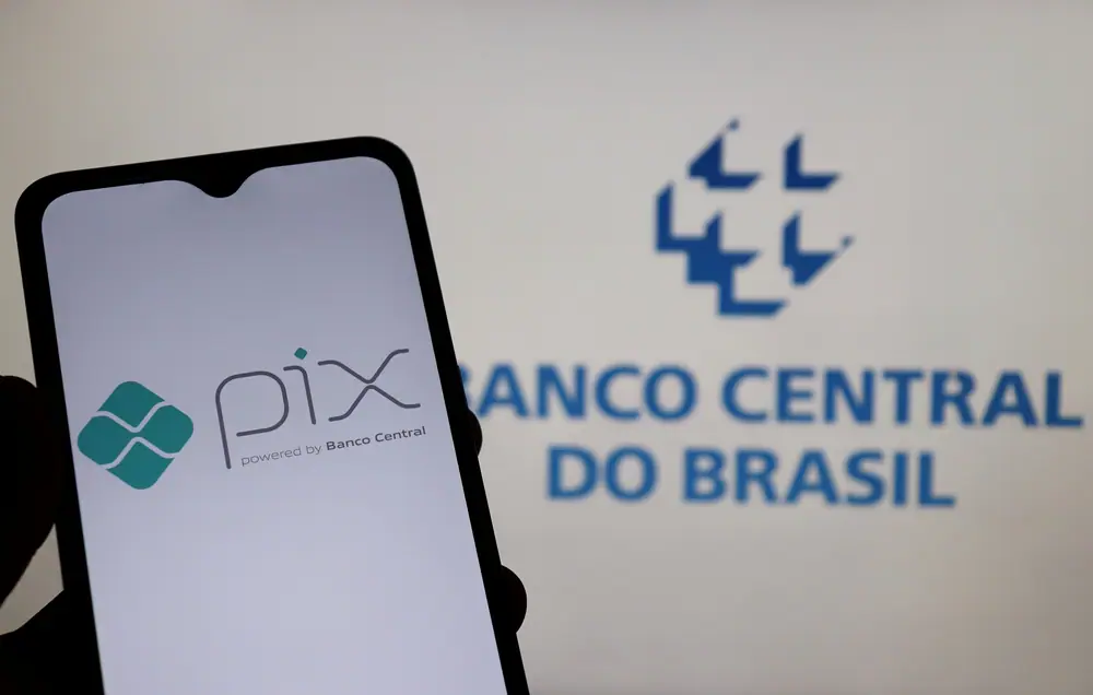 Celular com o app do Pix aberto, com a logo do Banco Central ao fundo