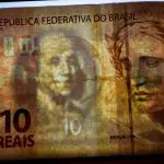 Uma cédula do real sobre uma imagem de dólar
