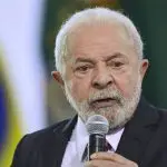 O presidente Luiz Inácio Lula da Silva fala, ao microfone, durante evento oficial; ele está com semblante sério, além de vestir paletó preto, camisa social branca e gravata vermelha. A foto é de Marcelo Camargo, da Agência Brasil