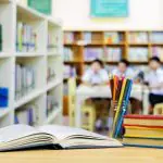 Livros e lápis em alusão à materia de gestão escolar entre diretores