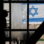 Uma pessoa caminha perto de um prédio residencial danificado, depois que o Hezbollah lançou centenas de foguetes e drones em direção a Israel - 25/8/2024 | Foto: Ammar Awad/Reuters