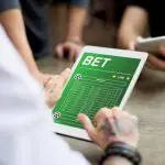 Imagem mostra um homem interagindo, via tablet, com uma plataforma de apostas on-line, as chamadas bets