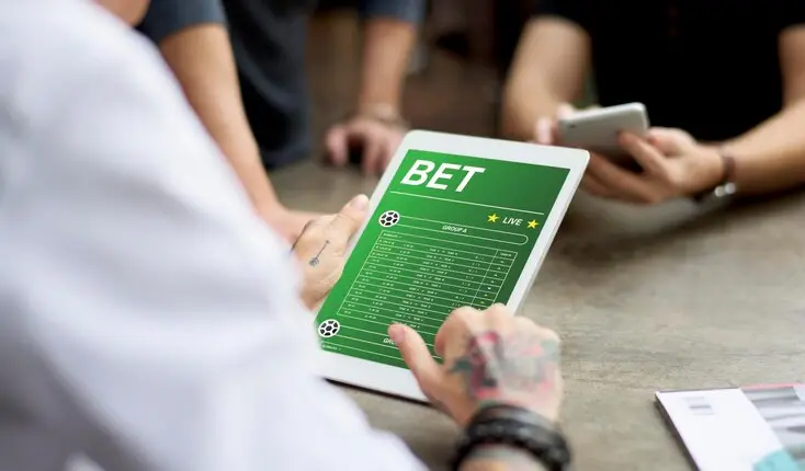 Imagem mostra um homem interagindo, via tablet, com uma plataforma de apostas on-line, as chamadas bets