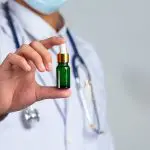 Médico máscara e estetoscópio mostra medicamento