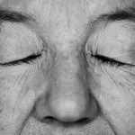 Imagem mostra um senhor, em preto e branco, com os olhos fechados. Foto ilustra reportagem sobre envelhecimento