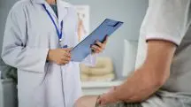 Médica com um paciente em cima da maca; ele está sentado e com as mãos sobre as pernas | Foto: Reprodução/Freepik