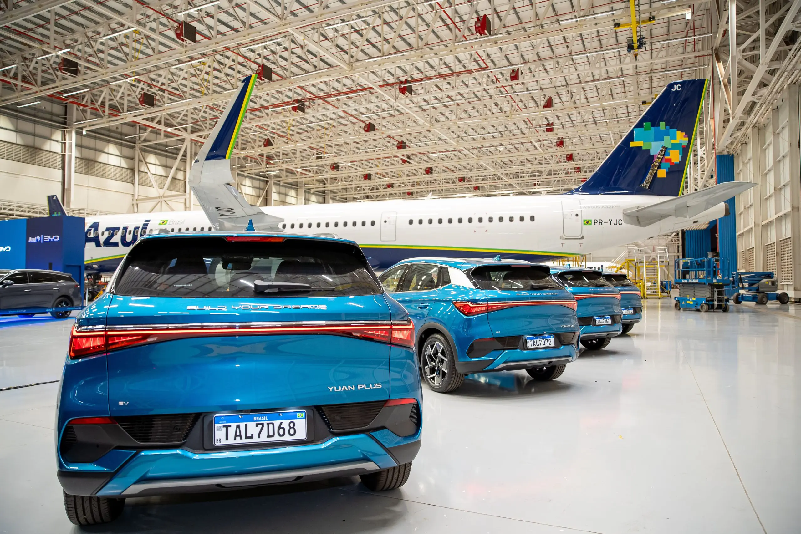Carros da BYD com o avião da Azul ao fundo