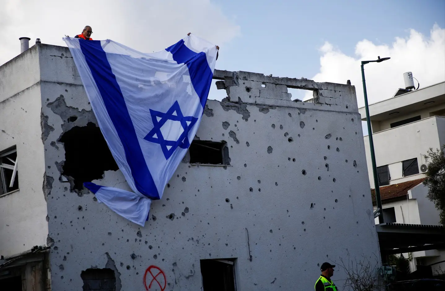 Homens israelenses penduram uma bandeira israelense sobre um prédio danificado, que foi atingido por um foguete do Líbano - 22/9/2024 | Shir Torem/Reuters