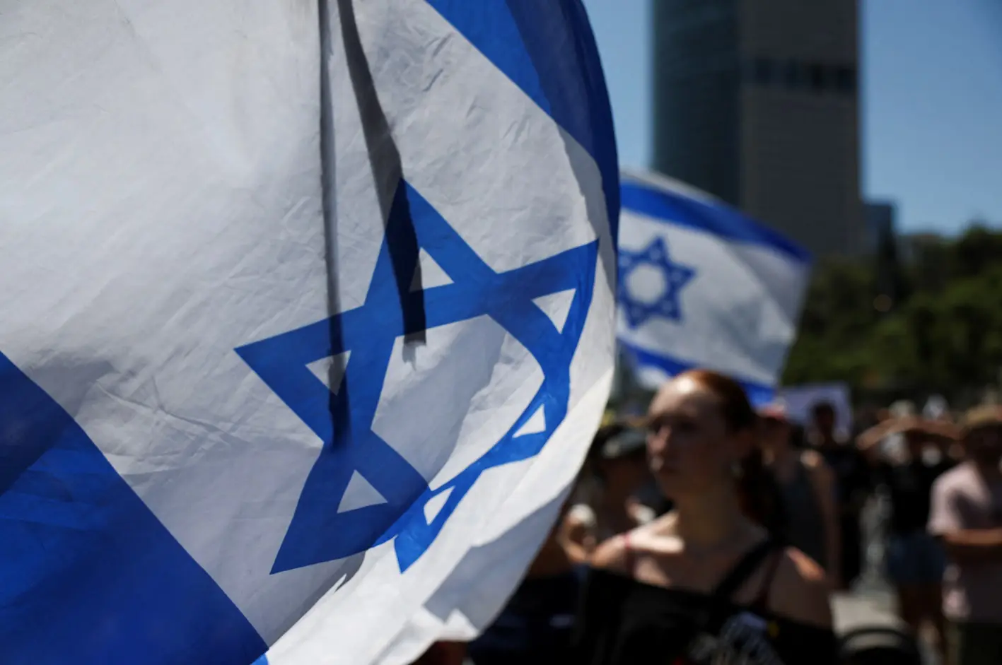 Uma bandeira israelense tremula, enquanto manifestantes se reúnem do lado de fora do Ministério da Defesa, para mostrar apoio aos reféns que foram sequestrados durante o ataque de 7 de outubro - 2/9/2024 | Florion Goga/Reuters