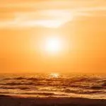 Foto meramente ilustrativa para conteúdo sobre onda de calor; na imagem, o sol aparece ao fundo, com registro do mar em primeiro plano