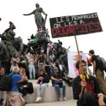 Esquerdista segura cartaz em que se lê 'os monarcas, nós os decapitamos' na Place de la Nation, em Paris | Foto: Reprodução/Redes sociais