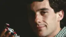 Ayrton Senna segura um modelo em escala 1:64 de seu primeiro carro vencedor do Campeonato Mundial de F1 | Foto: Reprodução/Wikimedia Commons