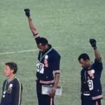 Gesto antirracista de Tommie Smith e John Carlos repercutiu no mundo todo | Foto: Angelo Cozzi/Wikimedia Commons