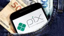 Notas de dinheiro e celular com a logo do Pix aberto