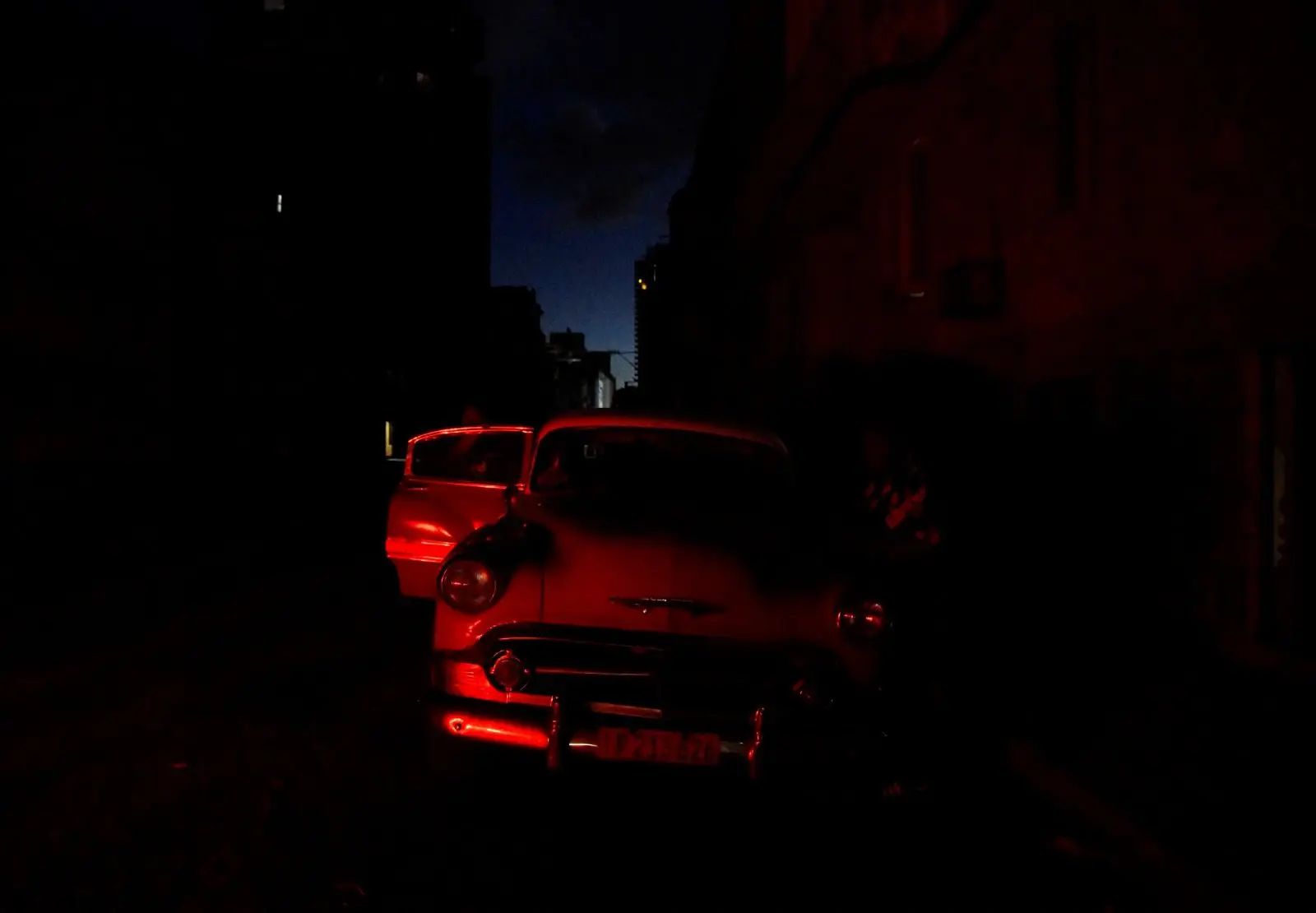 Um homem limpa seu carro antigo durante o apagão em Cuba | Foto: Norlys Perez/Reuters