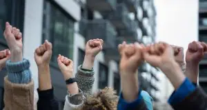 Pessoas protestam de braços levantados