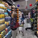 black friday 2024 - uma senhora no corredor de um mercado busca um item na prateleira de cima
