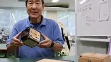 Cientista da Universidade de Kyoto, no Japão, mostra o satélite de madeira: material pode ser solução para construções mais sustentáveis no espaço | Foto: Reprodução/Twitter/X