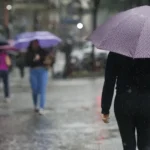 Pessoas andando com guarda-chuva na rua