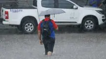 Homem caminha na chuva, em área alagada, em alusão ao alerta do Inmet