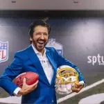 O prefeito de São Paulo, Ricardo Nunes, segurando a bola da NFL e um capacete de futebol americano. O prefeito sorri, durante coletiva de imprensa sobre o retorno da NFL ao Brasil